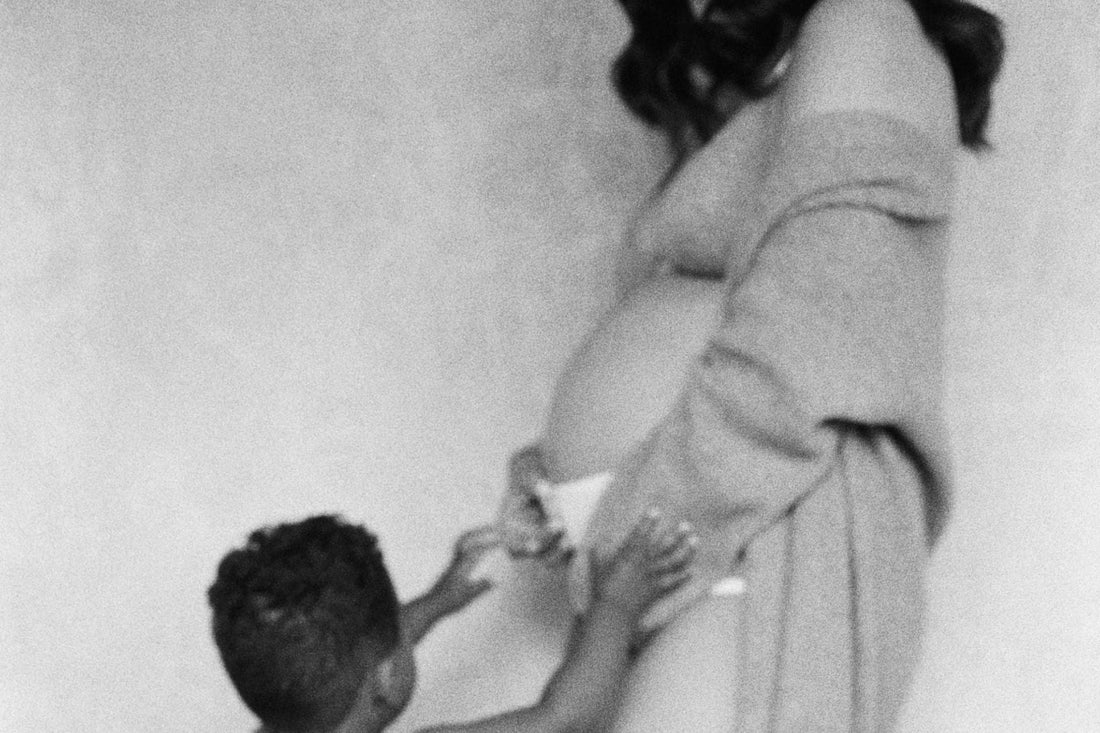 black and white photo of pregnant woman in underwear touching belly with a small child beside her