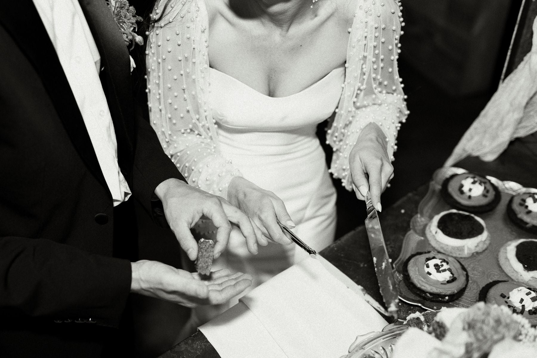 black and white photo of newly married couple cutting wedding cake