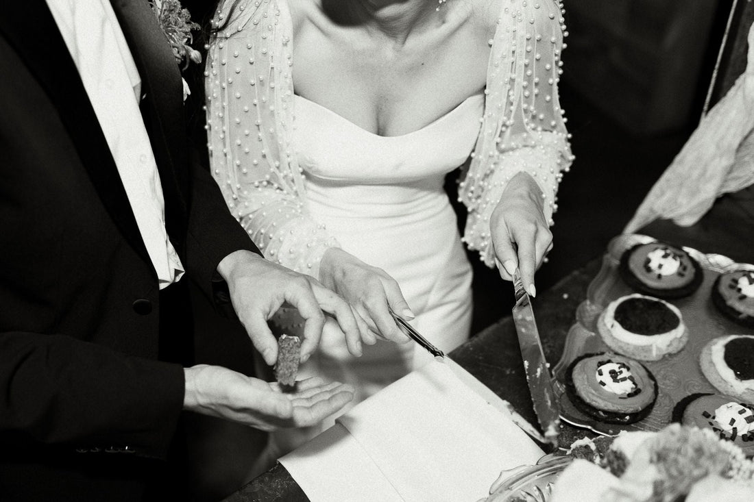 black and white photo of newly married couple cutting wedding cake