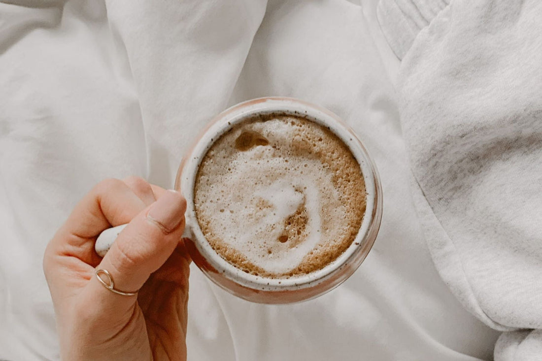 woman holding coffee in bed